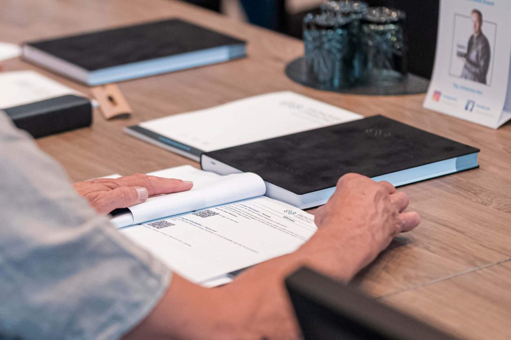 Gronover Consulting Mastermind Juli 2025 Unternehmer schaut Unterlagen des Vortrags durch
